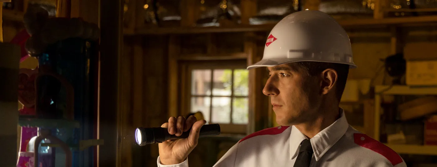 A VectorX specialist inspecting for rodents with a flashlight in a basement